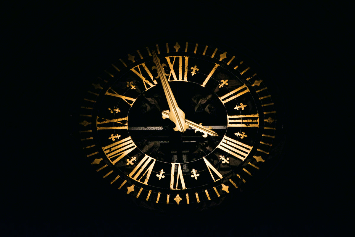 Reloj analógico en la oscuridad, con manecillas doradas iluminadas