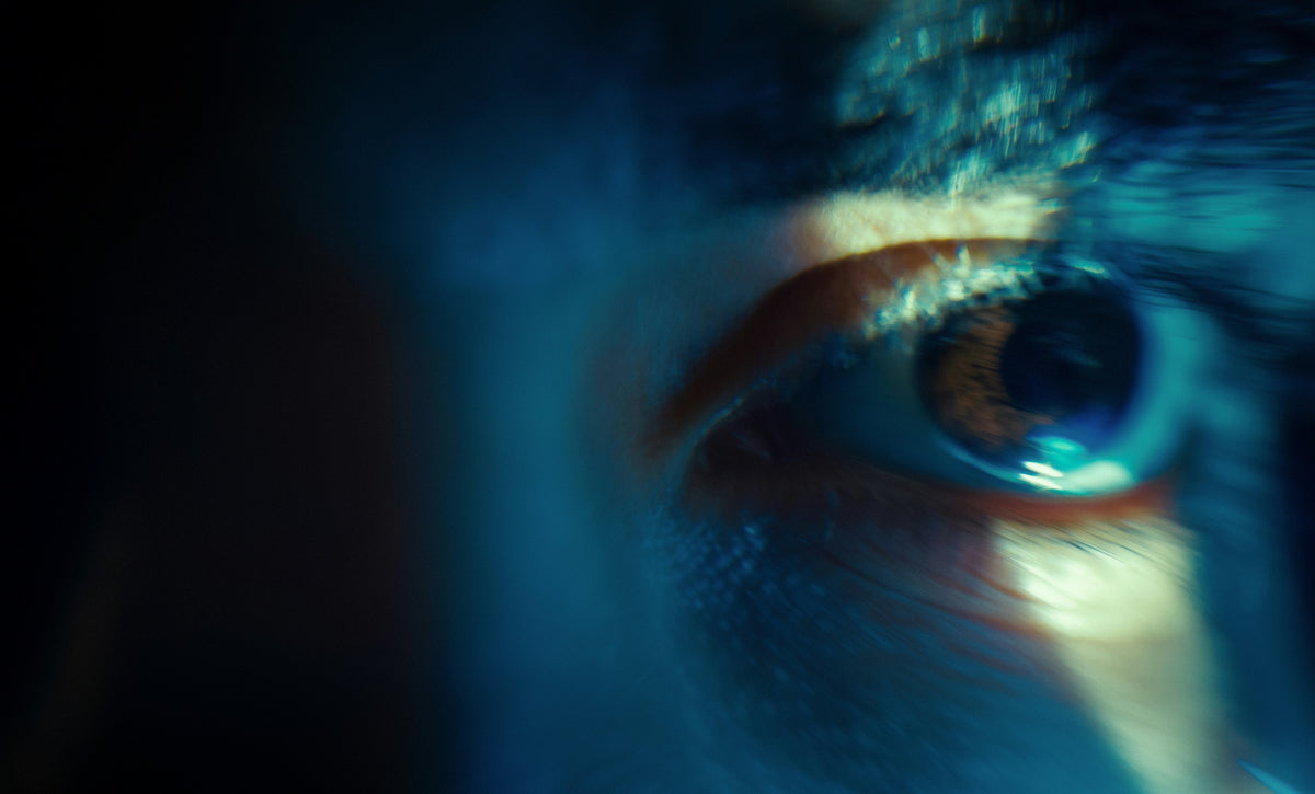Ojo humano iluminado por luz azul en la oscuridad