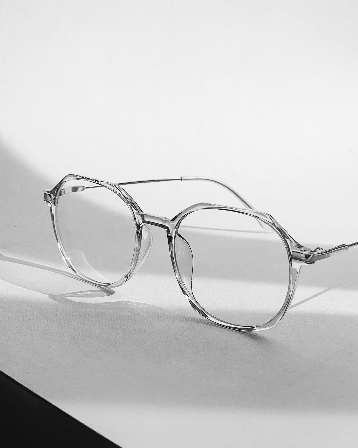 Gafas de lente transparente sobre una mesa, en blanco y negro