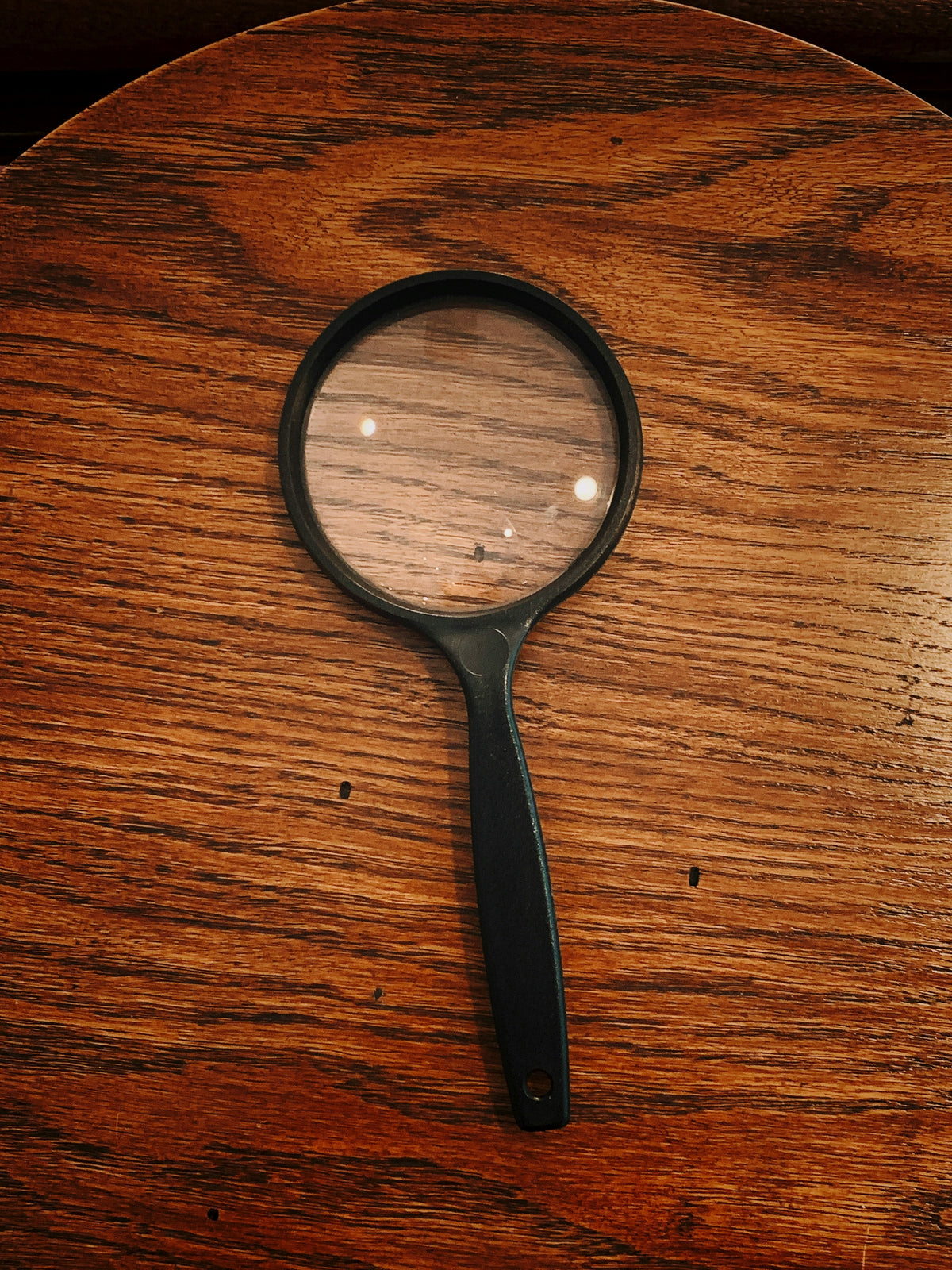 Lupa sobre una mesa de madera, en tonos cálidos